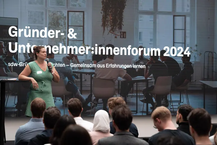 Begrüßung vor der Leinwand mit dem Motto des GUF 2024